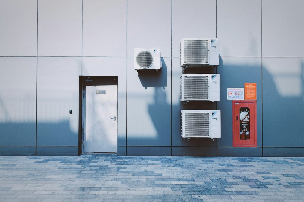 Row of air conditioning outdoor units mounted on a grey wall