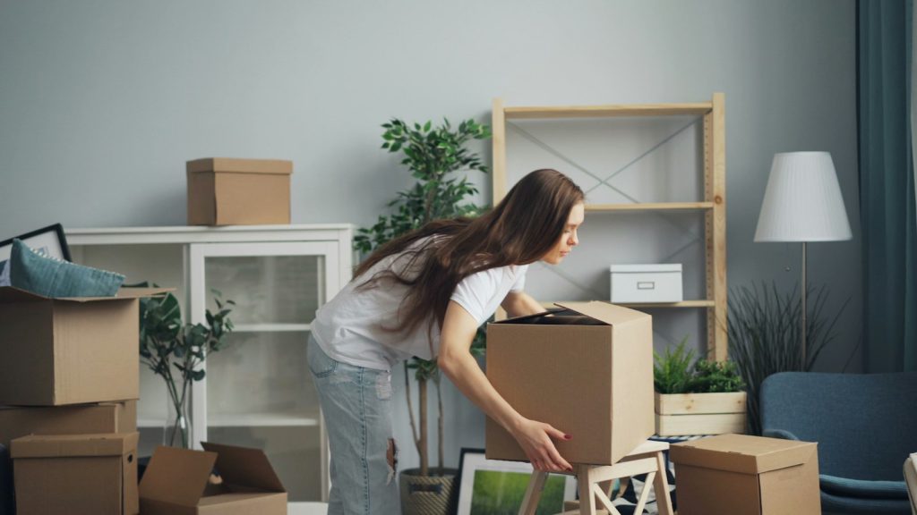 Person carrying moving boxes in a living room